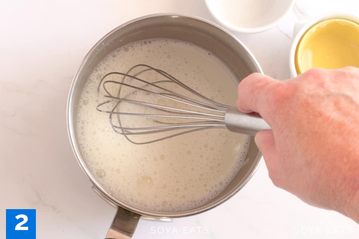 A whisk mixing liquid in a saucepan.