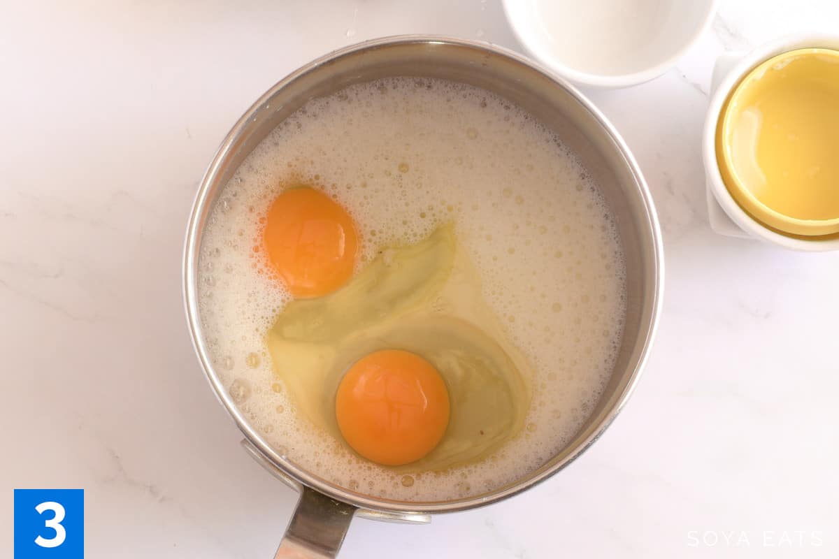 Two eggs in a saucepan with soya milk.
