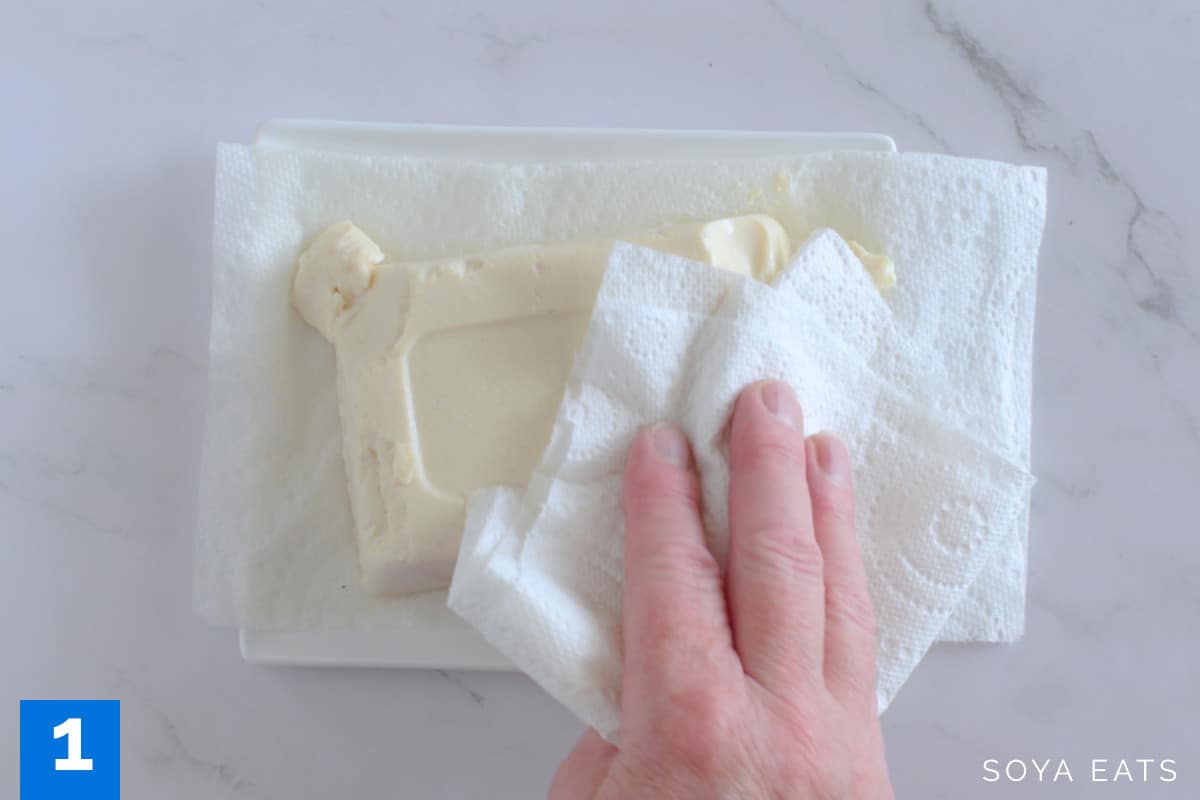 A block of silken tofu being patted dry.