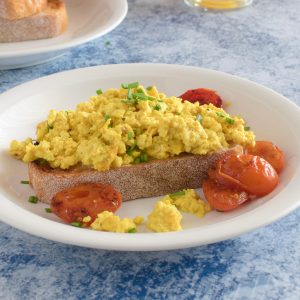 A breakfast plate of toast with scrambled silken tofu and pan fried tomatoes.