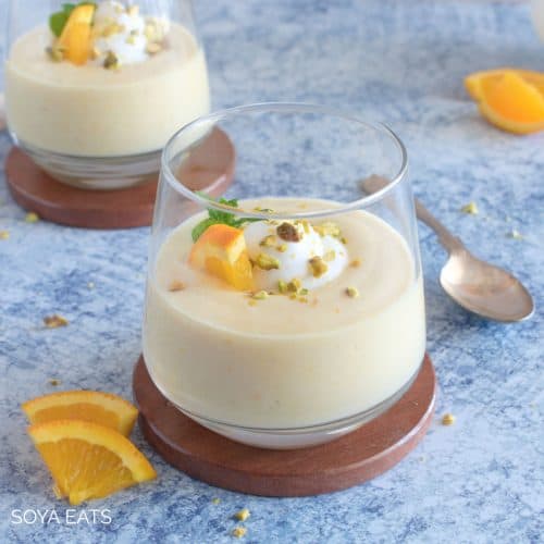 Orange pudding garnished with an orange slice, mint leaves, cream and chopped nuts.