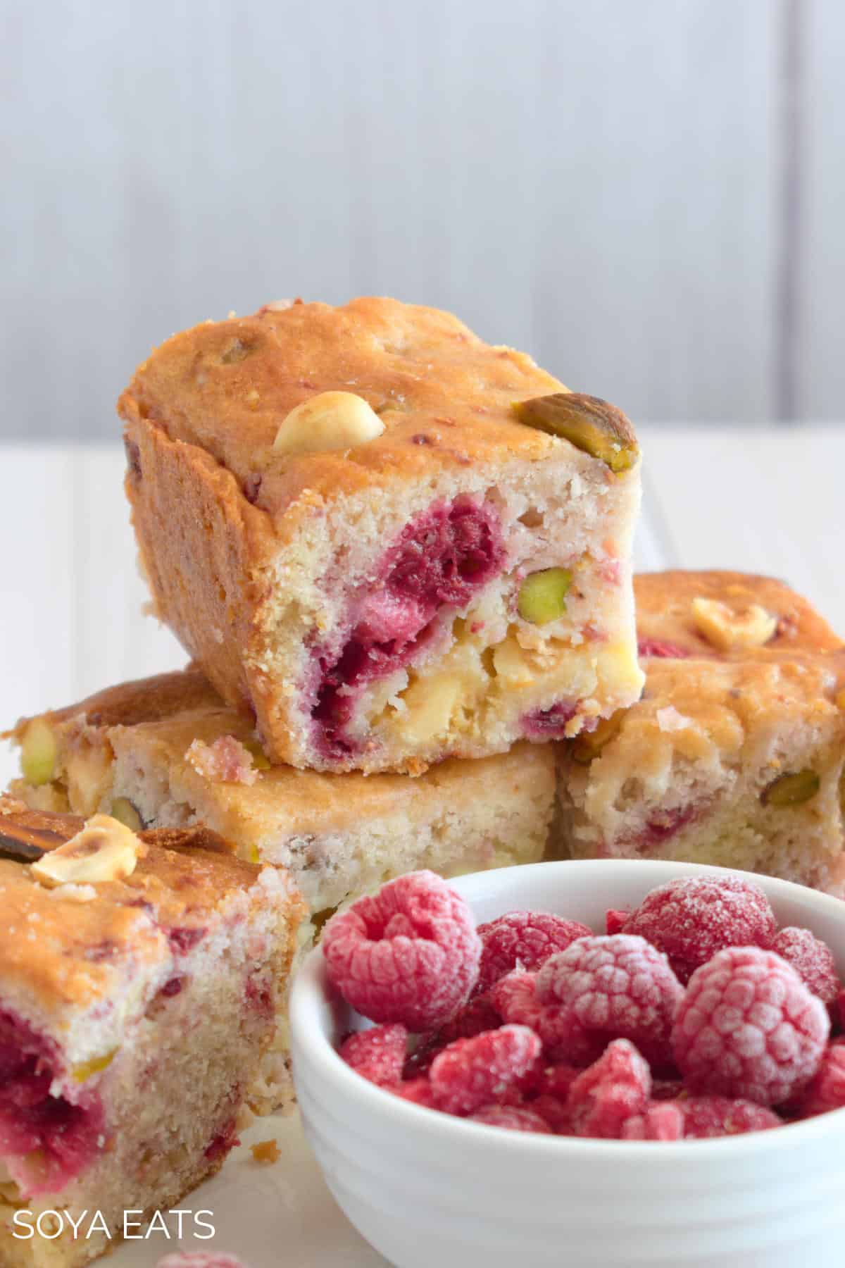 Blondies with a bowl of frozen raspberries.