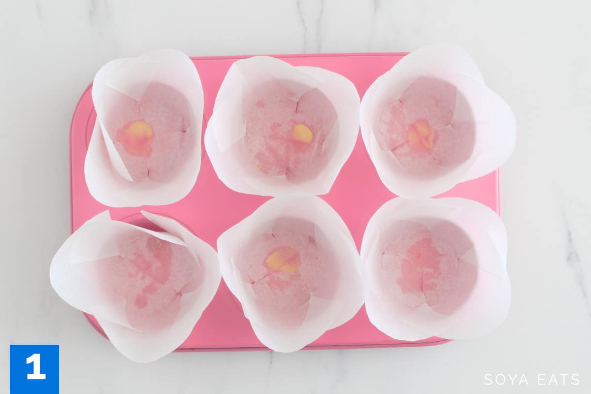 A pink muffin tin with muffin liners.