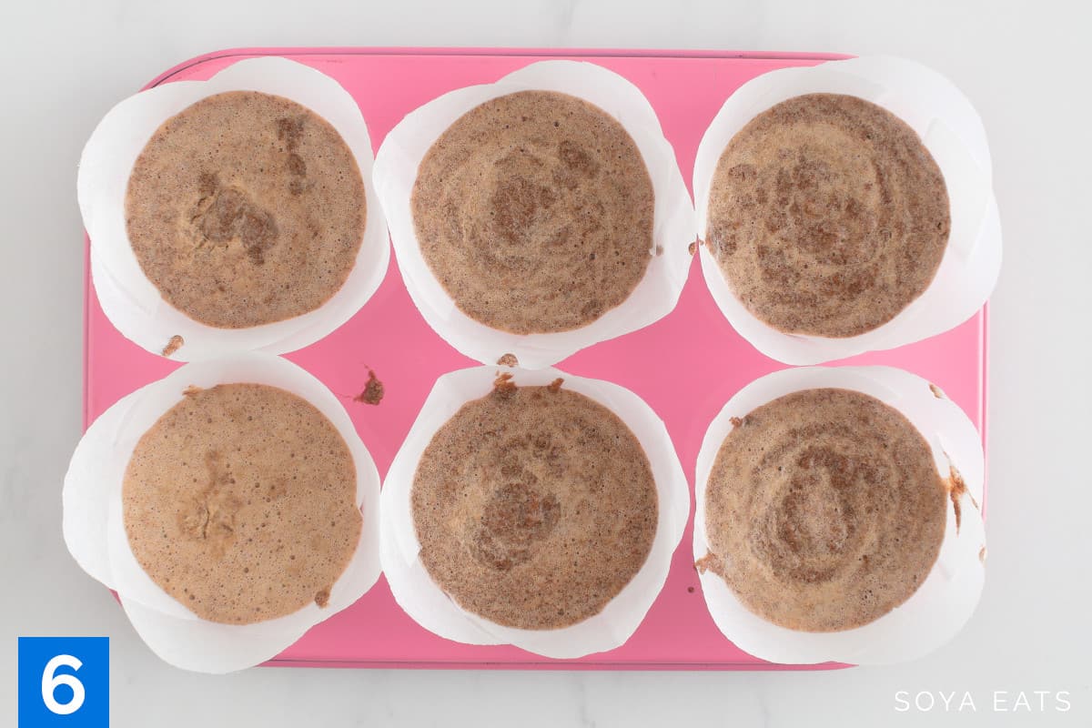 Gluten free okara chocolate cake batter poured into muffin cases in a pink muffin tin.