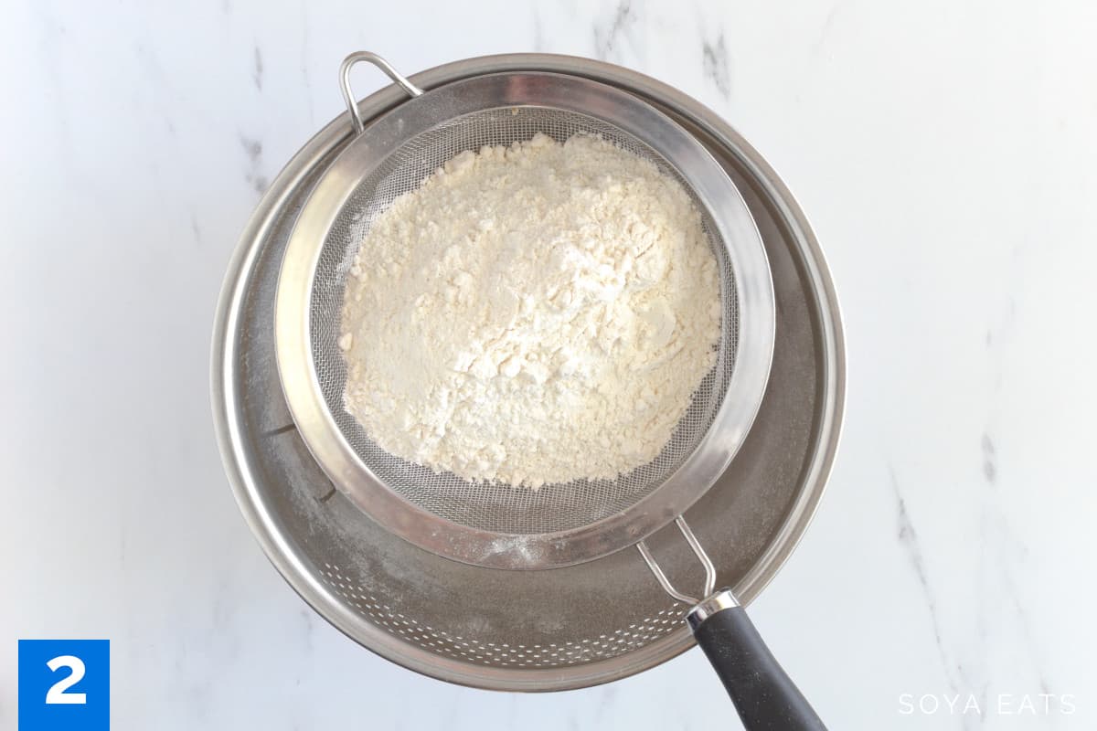 Flour in a sieve over a mixing bowl.