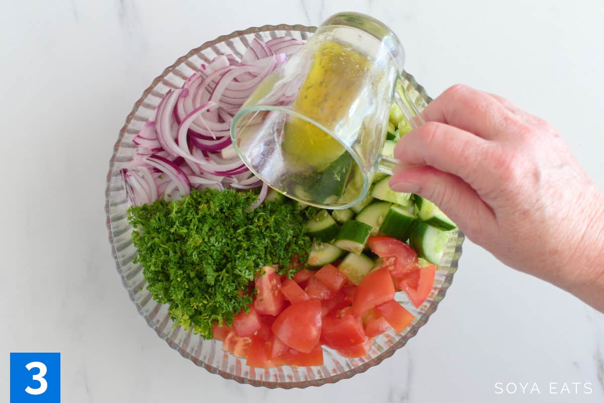 Salad dressing being poured over a salad.
