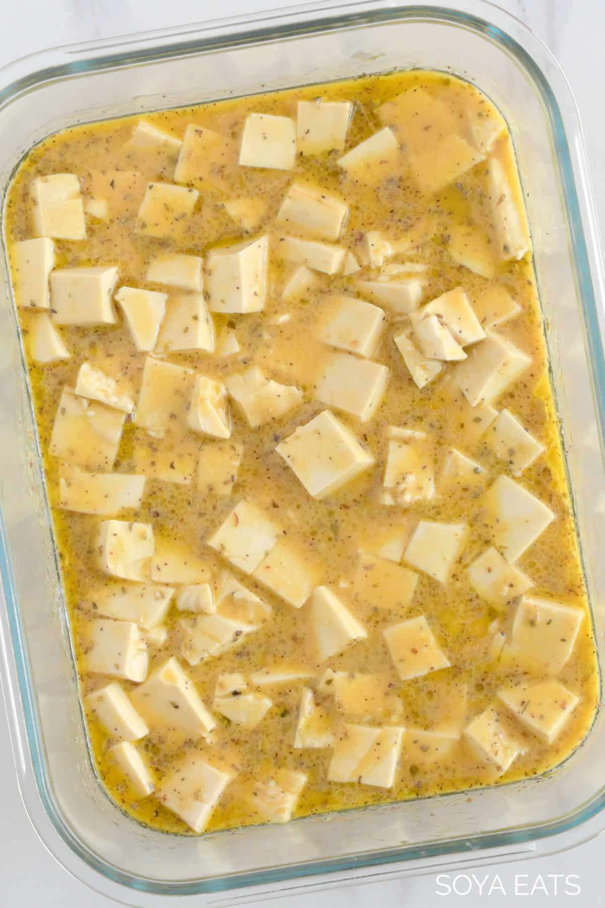 A close up of tofu marinating in a glass dish.